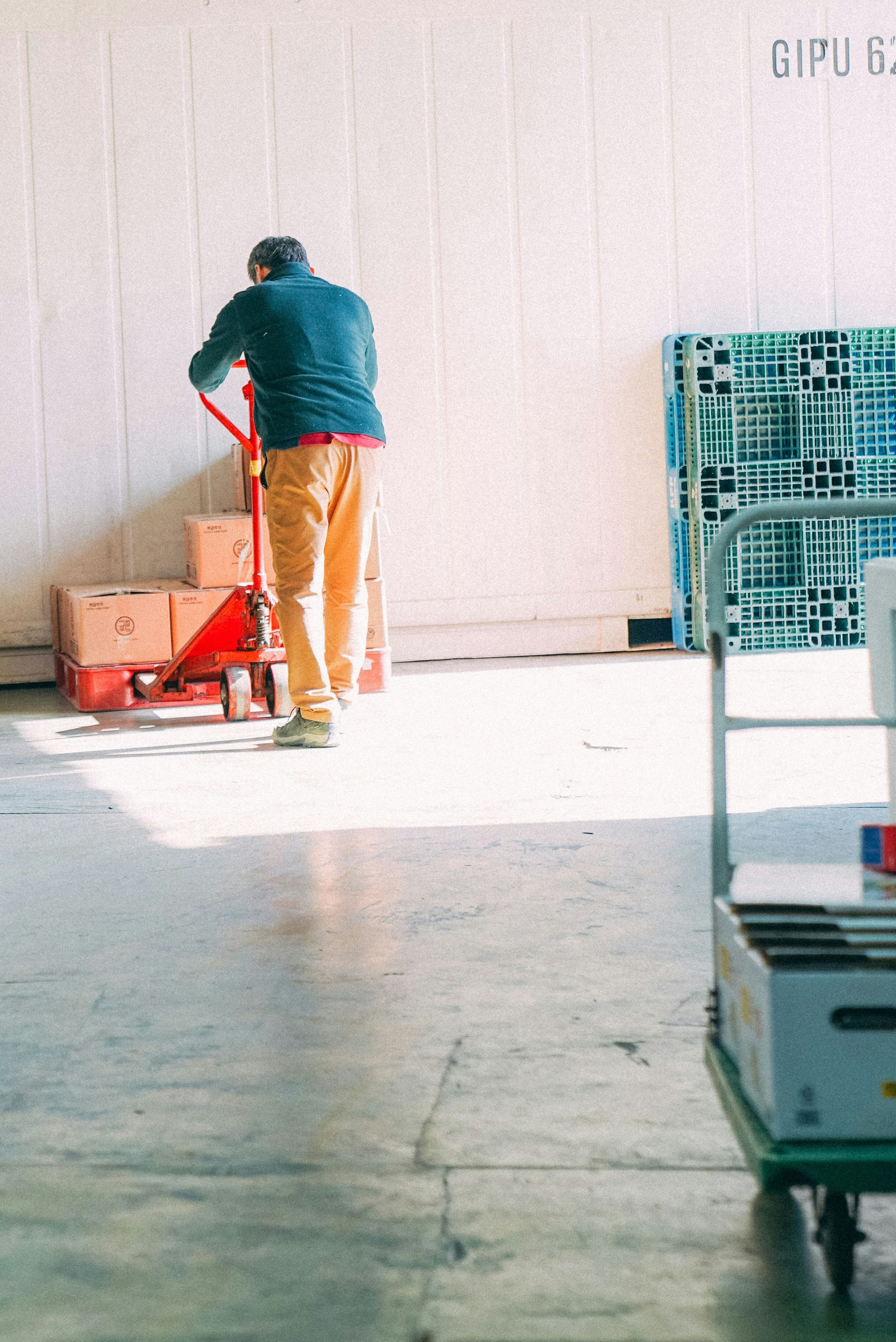 a man standing next to a red cart in a garage